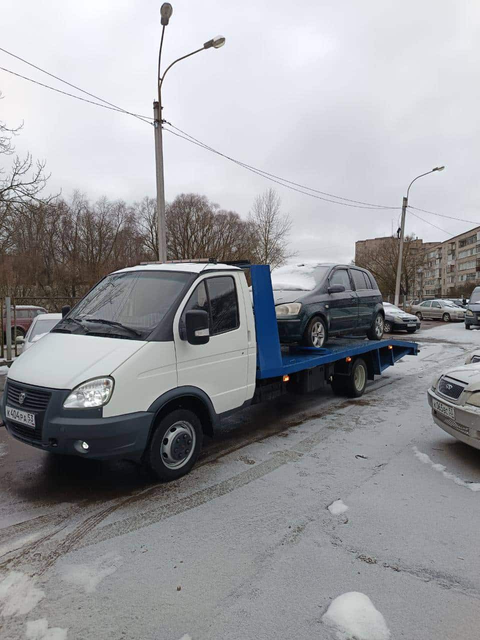 Эвакуатор с хэтчбеком на платформе зимой в Великом Новгороде
